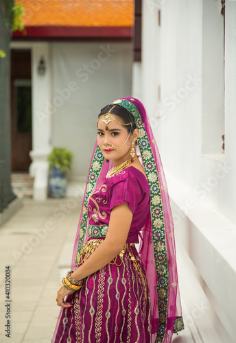 Portrait Asian woman in a margenta Indian tradition sari, she is looking at a camera next to the white wall