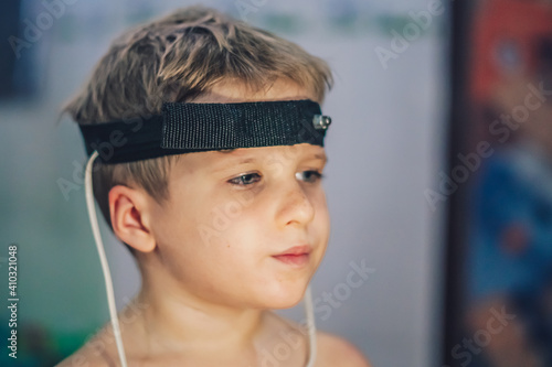 Express biofeedback microcurrent rezonans health of organs diagnostic. Sick child boy wear bioresonance head electrodes reveal disease causing bacteria via electromagnetic fields based on biofeedback