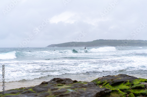 Male man catching waves surfing at Maroubra beach on a wet winters day, cloudy day, overcast
