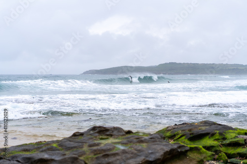 Male man catching waves surfing at Maroubra beach on a wet winters day, cloudy day, overcast