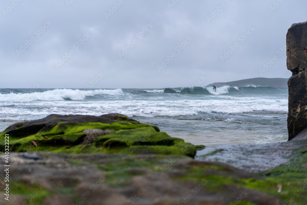 Male man catching waves surfing at Maroubra beach on a wet winters day, cloudy day, overcast