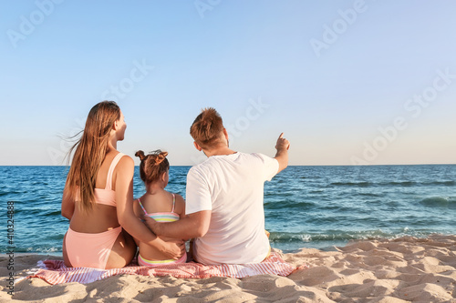 Happy family sitting on sea...