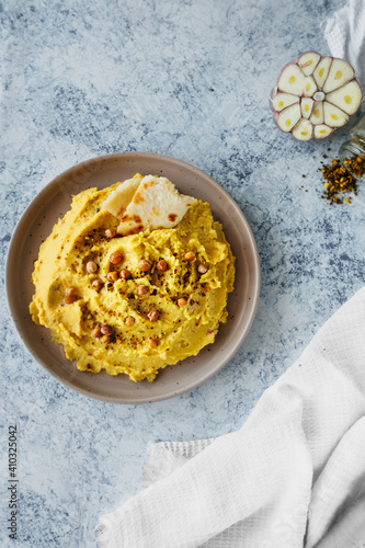 beautiful serving of chickpea hummus with olive oil, garlic, spices and roasted grains on kitchen table with cotton napkin, vertical food content, simple recipes cooking at home, selective focus photo