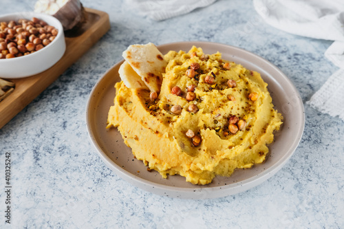 beautiful serving of chickpea hummus with olive oil, garlic, spices and roasted grains on kitchen table with cotton napkin, food blog, simple recipes cooking at home, selective focus
