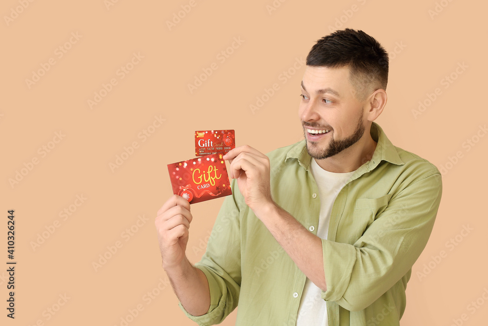 Handsome man with gift card on color background Handsome man with gift card on color background