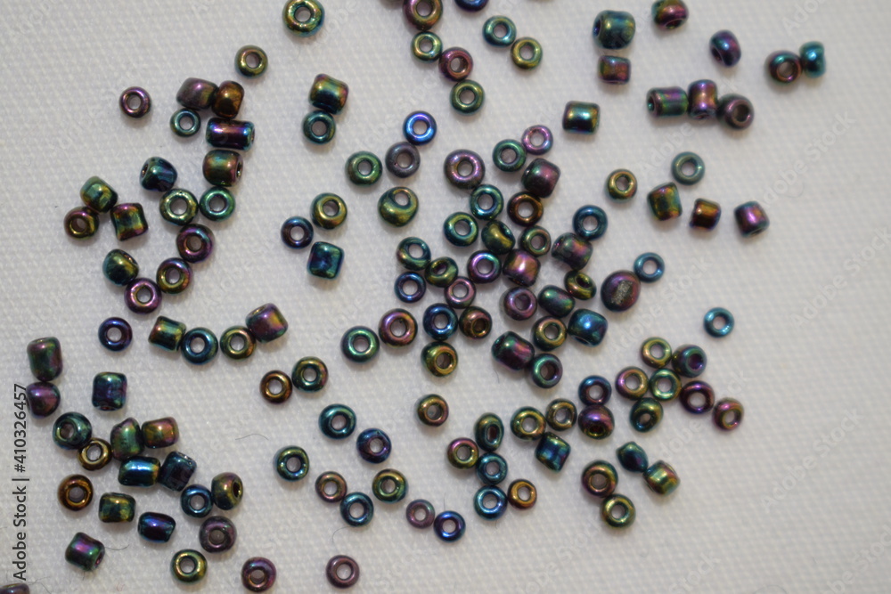 Dark beads scattered on a white background. Materials for needlework. Dark beads scattered on a white background. Materials for needlework.