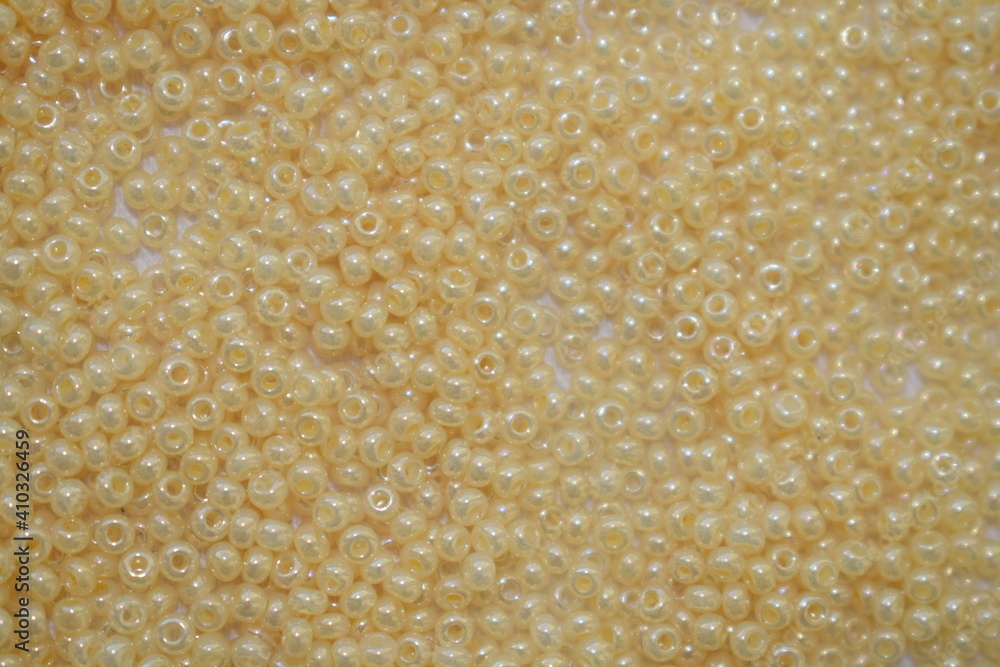 Beige beads scattered on a white background. Materials for needlework.