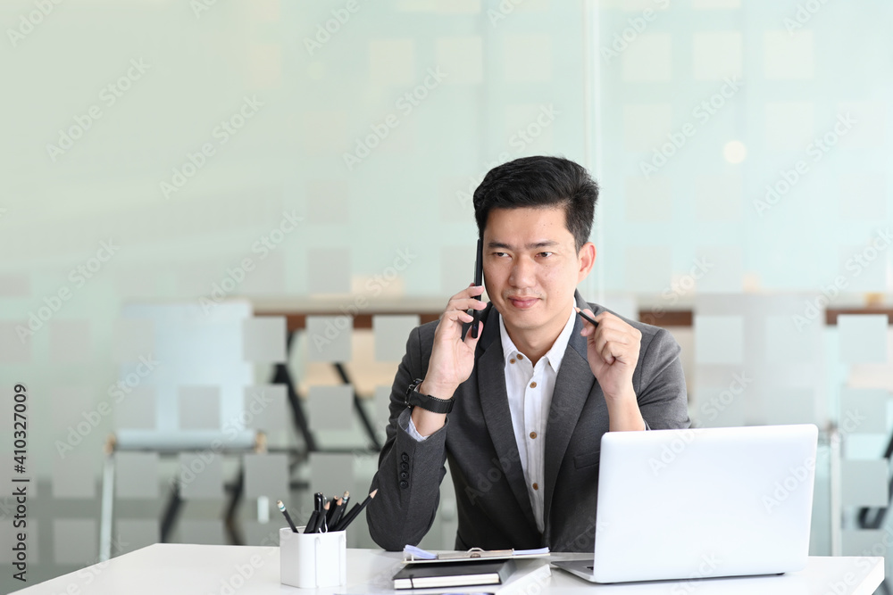 Businessman talking on mobile phone while sitting at his personal office.