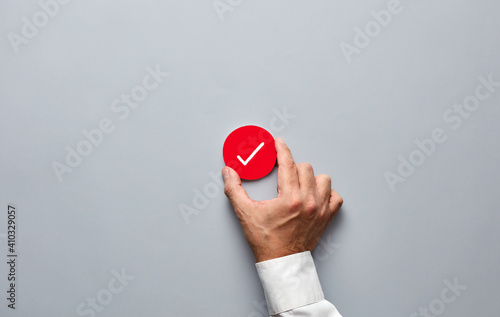 Businessman hand holding a red badge with a check mark. Approve, verify or confirm in business photo