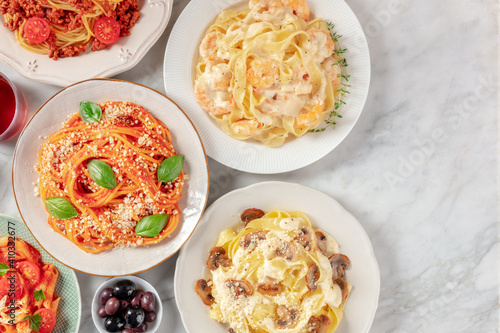 Italian pasta assortment. Spaghetti with tomato sauce and cheese, mushroom pappardelle, and other pastas, overhead flat lay shot with copy space