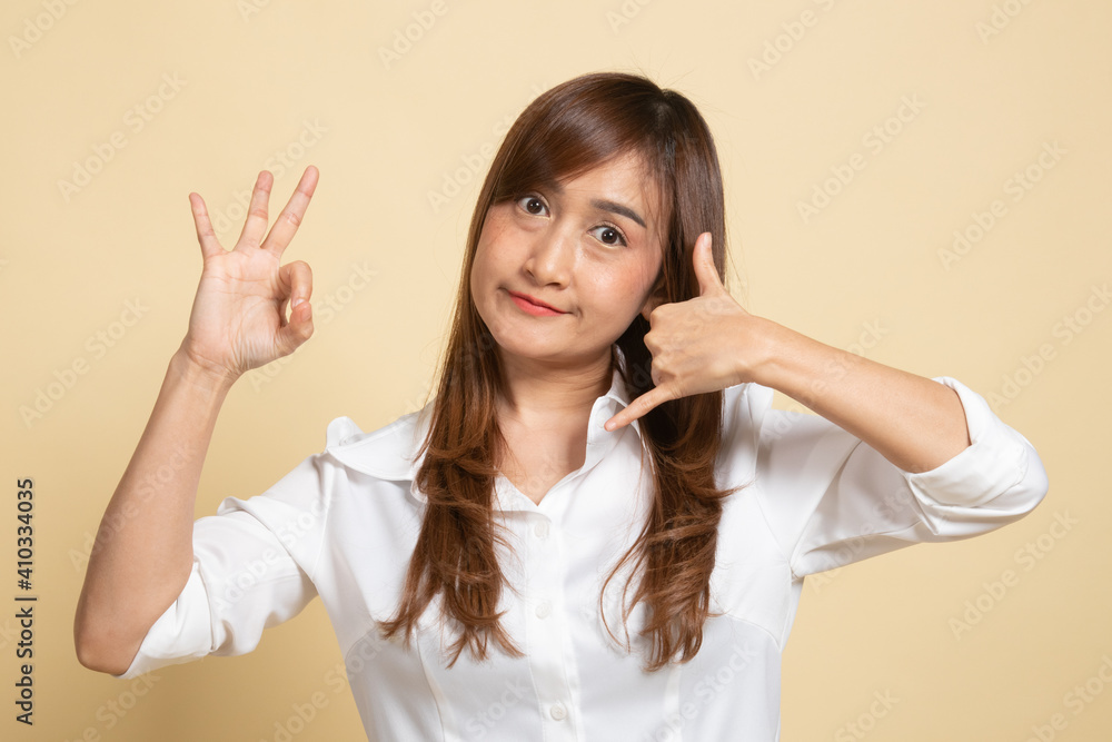 Young Asian woman show with phone gesture and OK sign. Young Asian woman show with phone gesture and OK sign.