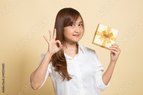 Young Asian woman show OK with a gift box. © halfbottle