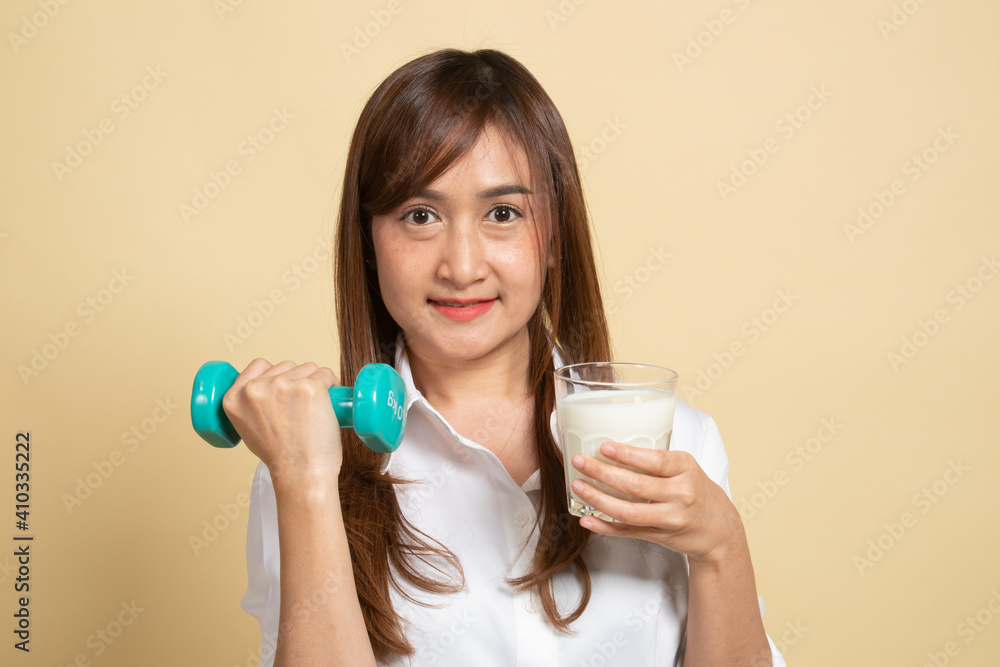 Healthy Asian woman drinking a glass of milk and dumbbell.