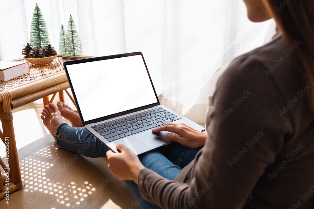 Mockup image of a woman working and touching on laptop touchpad with blank white screen at home Mockup image of a woman working and touching on laptop touchpad with blank white screen at home