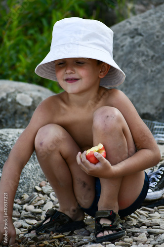 Boy in panama eating apple in summer 
