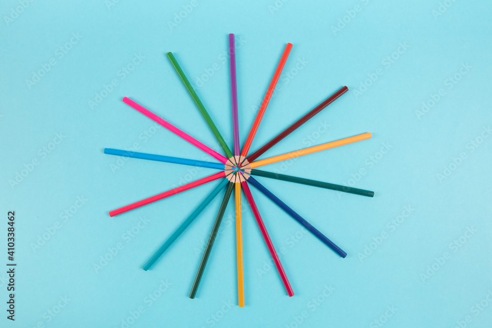 Circle made of colorful pencils on blue background
