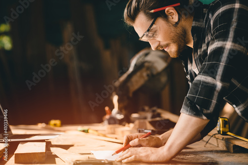Foto Happy Carpenter smiling to sketch design wooden furniture in wood workshop professional look high skill real authentic handcrafted working people