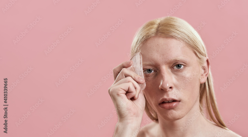 Young caucasian man using quartz tool for face massage Young caucasian man using quartz tool for face massage