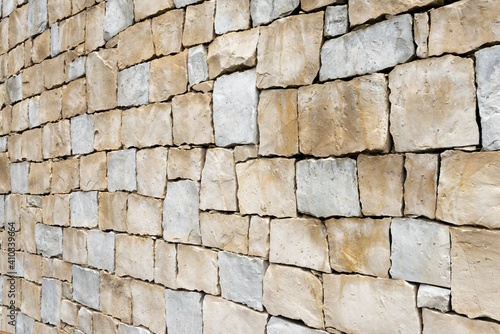Light warm yellow sandstone wall made of square blocks seen in perspective.
