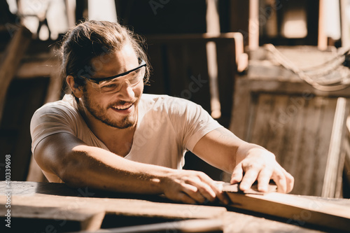 Young Carpenter happy working to making woodcraft furniture in wood workshop look professional high skill real people workman. photo