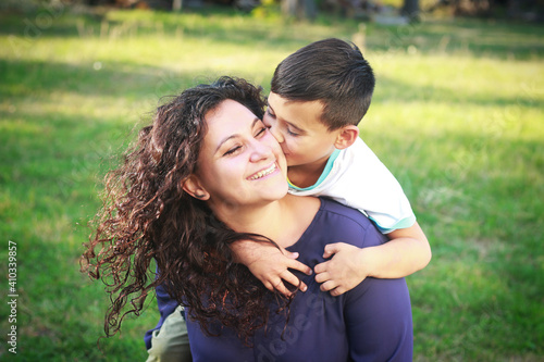 Happy smiling mixed race mother and son spending time outdoors Cute child hugging and kissing mother