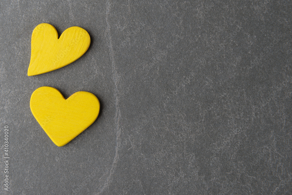 Two yellow decorative hearts on grey stone background with copy space. Valentine’s day trendy greeting Two yellow decorative hearts on grey stone background with copy space. Valentine’s day trendy greeting
