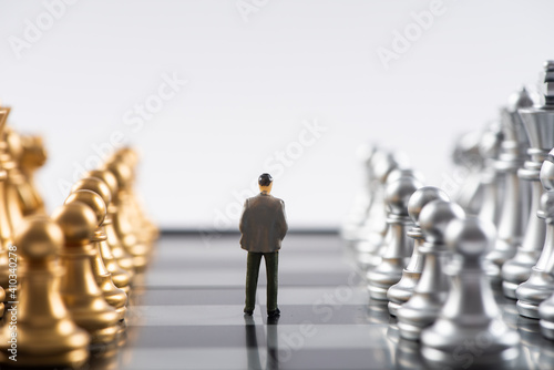 Business and Competition Concept. Businessman miniature figure standing on chessboard with chess pieces photo