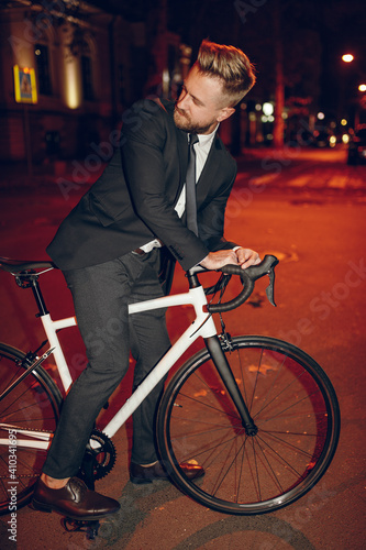Elegant businessman riding bicycle in night city