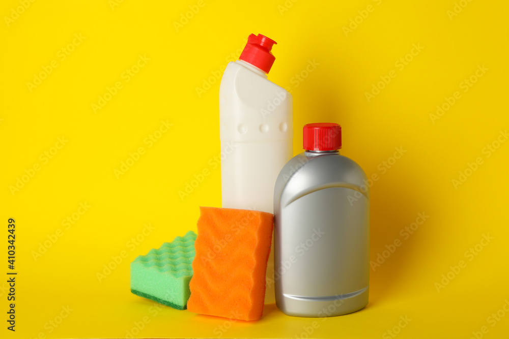 Detergents and sponges on yellow background, space for text
