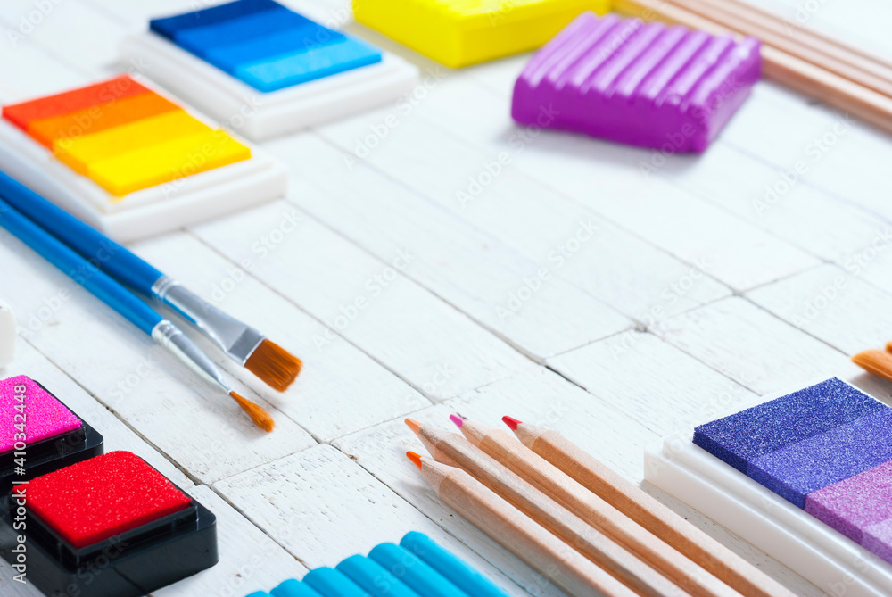 plasticine blocks, ink pads and pencils, brushes on white wood table plasticine blocks, ink pads and pencils, brushes on white wood table