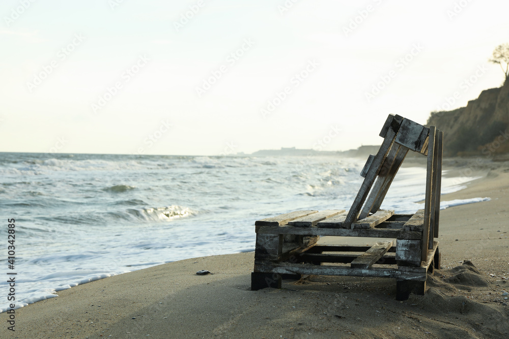 Wooden bench on sandy sea beach, space for text