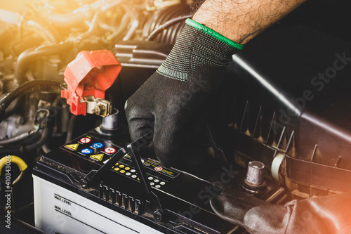 The Mechanic hand is pulling up an car old battery for replacement