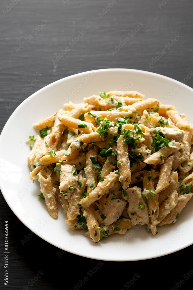 Homemade Chicken Alfredo Penne with Parsley on a black background, side view. Copy space.