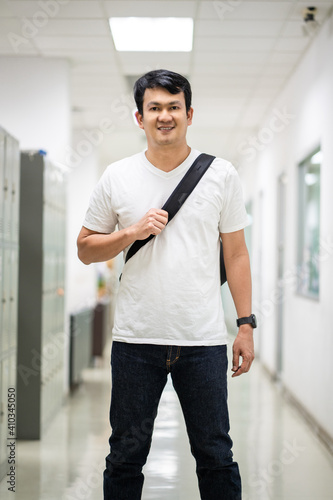 Portrait Asian man carry a black color strap bag on rear in office