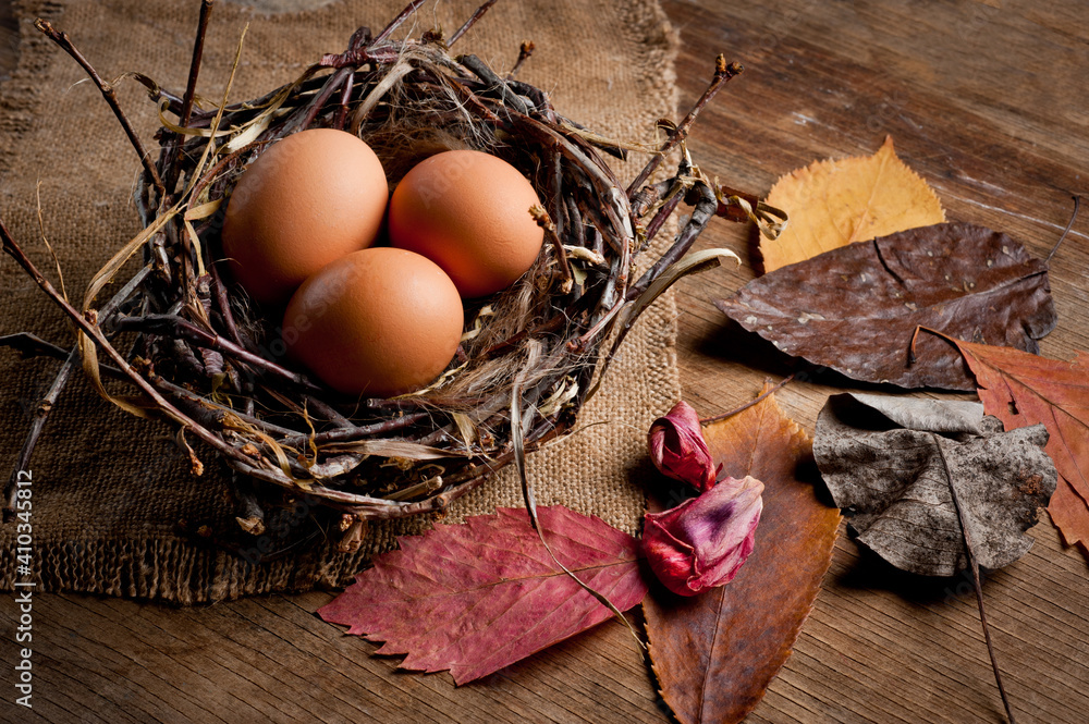 Chicken eggs in a wicker basket in the shape of a bird's nest, lying on an old wooden surface.
