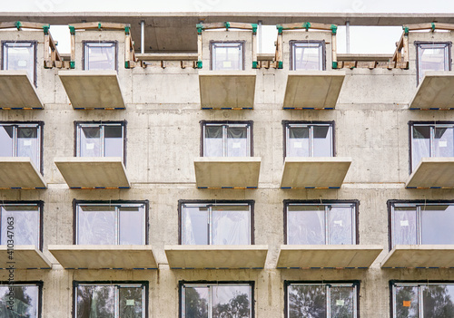 Construction site with a large residential building made of concrete slabs with a window and balcony.