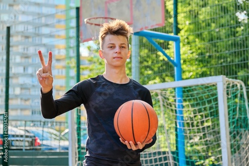 Guy teenager with basketball ball showing victory sign