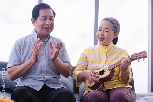 asian grandma playing ukulele with her friend in living room