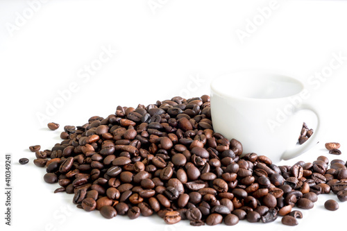 Dark roast coffee beans and the white cup background, top view