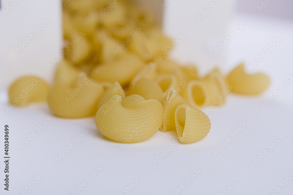 Italian durum wheat pasta poured from a white box on the table Italian durum wheat pasta poured from a white box on the table