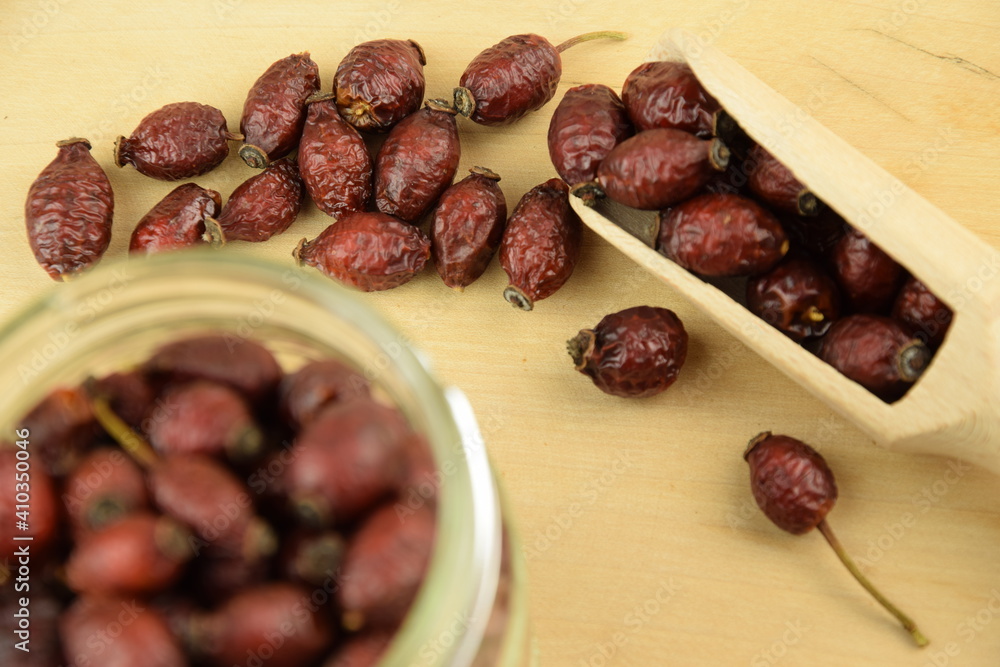 Rose hips, dried wild rose fruits on jar, natural wooden background, super food, healthy fruits, vitamin C and antioxidants resource Rose hips, dried wild rose fruits on jar, natural wooden background, super food, healthy fruits, vitamin C and antioxidants resource