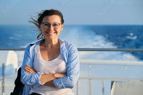 Beautiful happy confident mature woman on deck of ship, ferry, enjoying sea voyage