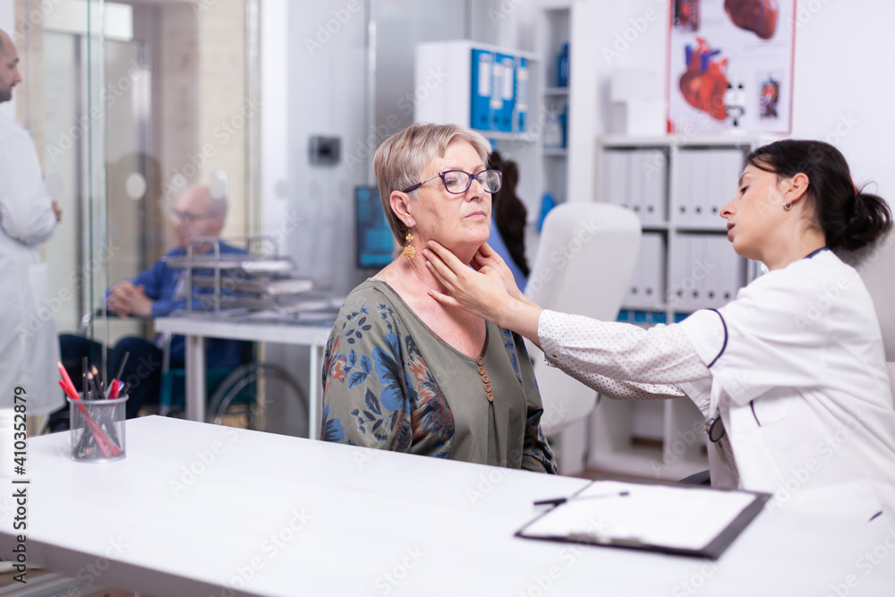 Obraz premium Professional physician checking neck lymph nodes of old woman, palpating senior woman. Elderly patient visiting doctor at hospital examining thyroid throat touching health at clinic, treatment medical