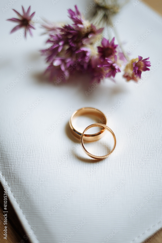 Two golden wedding rings and pink flowers on white background. Two golden wedding rings and pink flowers on white background.