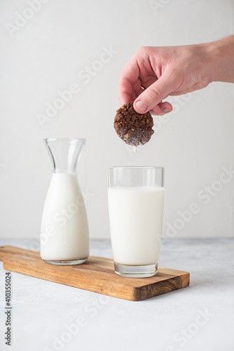 Healthy breakfast. Bottle and glass of milk and cereal cookies. A man dunks cookies in a glass of milk. White background. Copy space
