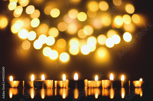 Burning candles with festive bokeh on a black background. Holiday concept. The concept of prayer and hope.