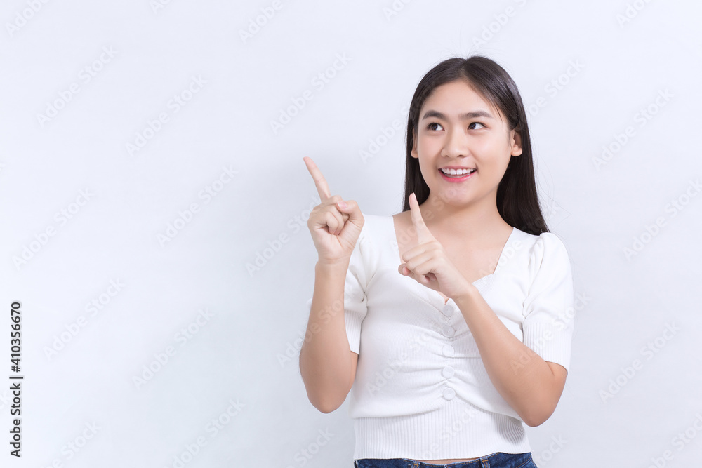 Asian woman in black long hair wears white shirt and shows point up to present something on white background. Asian woman in black long hair wears white shirt and shows point up to present something on white background.