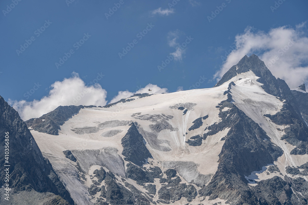 Obraz premium Emergency helicopter rescue skier hanging by rope from Grossglockner glacier in Austria summer