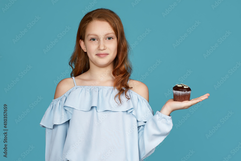 portrait of cute attractive child girl holding in hand delicious cupcake isolated over blue background portrait of cute attractive child girl holding in hand delicious cupcake isolated over blue background