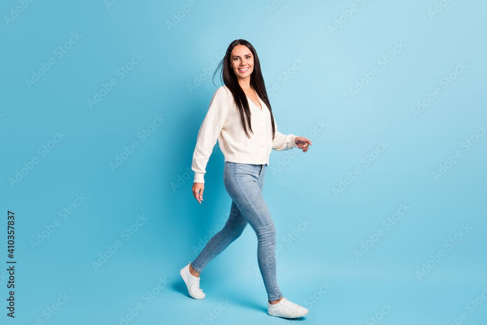 Full size profile portrait of charming person toothy smile walking look camera isolated on blue color background Full size profile portrait of charming person toothy smile walking look camera isolated on blue color background